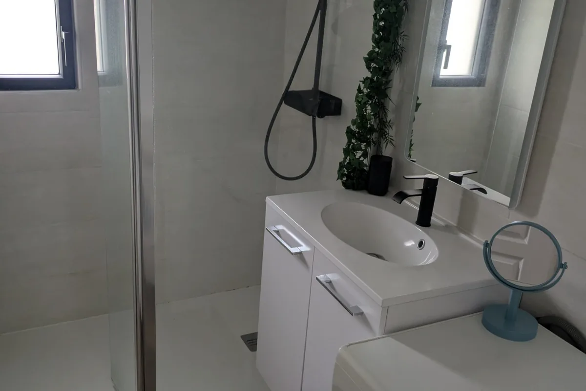 Salle d’eau moderne avec machine à laver, rangements et douche spacieuse